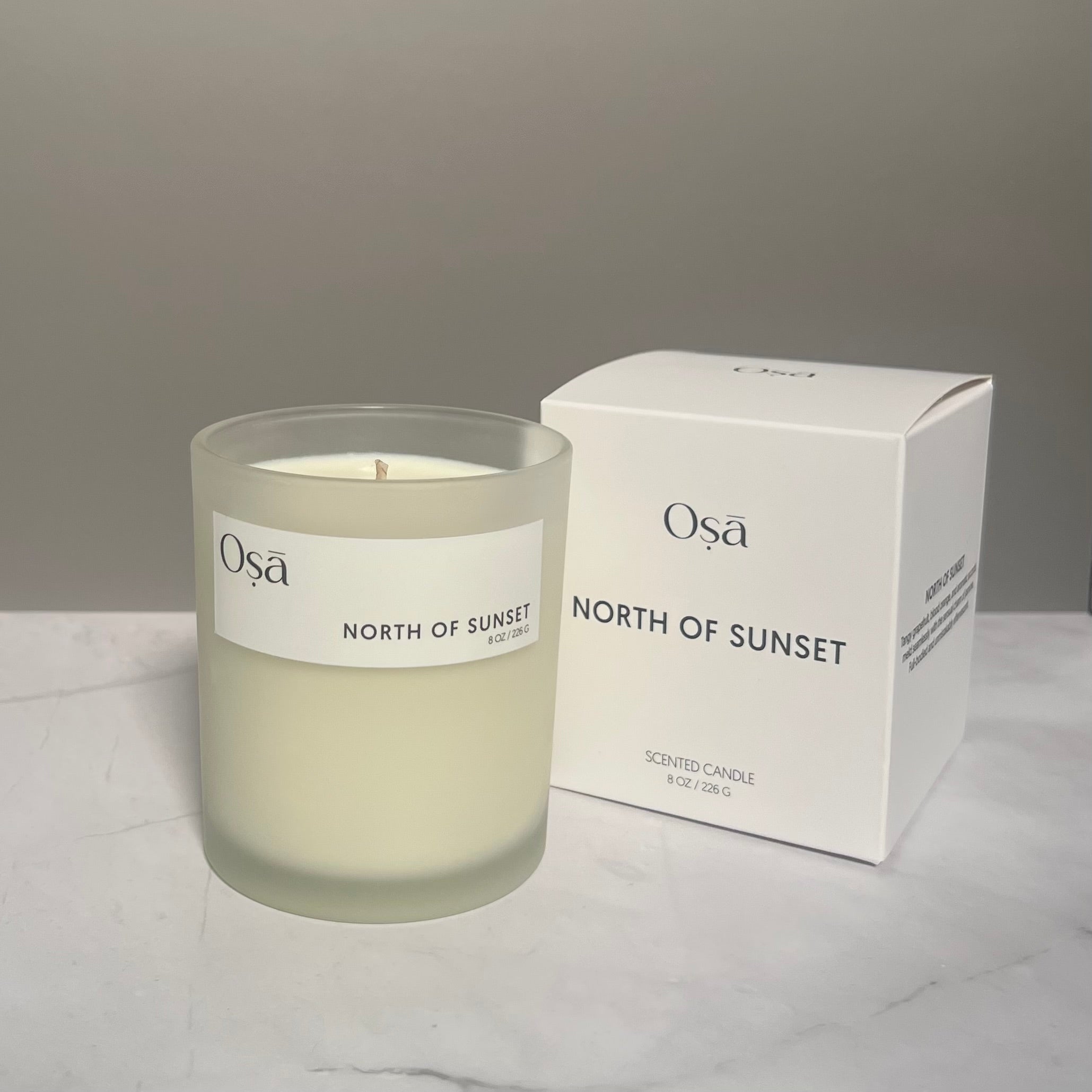 A candle and box with a label displaying Osa North of Sunset.