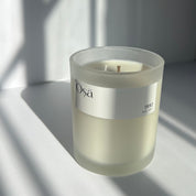 A candle in the sunlight with an Osa 1992 label displayed.