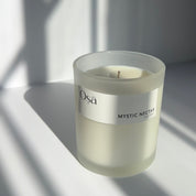 A candle in the sunlight with a label displaying Osa Mystic Nectar.