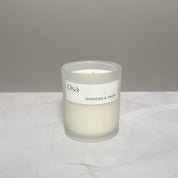 A candle on a countertop with an Osa Shadows & Smoke label displayed.